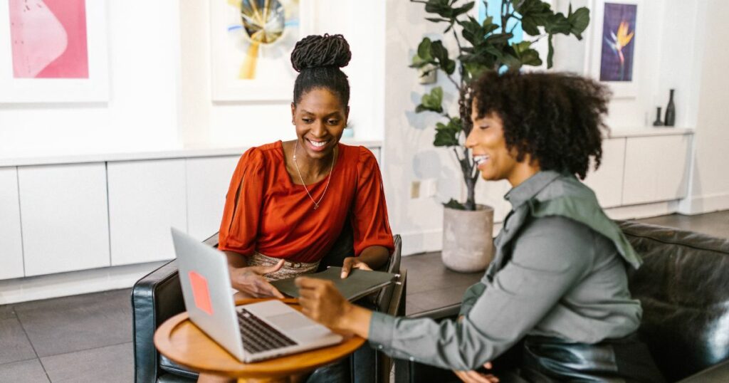 Two black women smiling and having a conversation at work