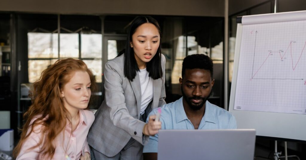 Two women and one man looking discussing work related topics, while looking at a computer screen.