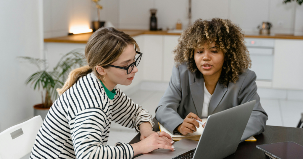 woman in stripe shirt using an ipad beside the woman with graycoat